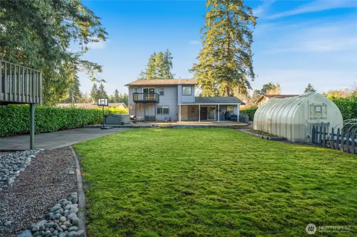 Nice sized fully fenced backyard with hottub, greenhouse, covered patio, play house and storage shed.