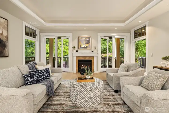 The living room centers on a Valor gas fireplace with marble surround, opening to the covered deck and lush nature views.