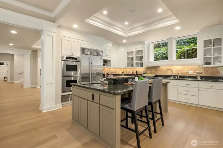 A chef's kitchen defined by Dacor double ovens and warming drawer, Sub-Zero refrigerator, dual Bosch dishwashers, slab granite counters, filtered water at the island, Insta-hot at the main sink, and generous pantry storage.