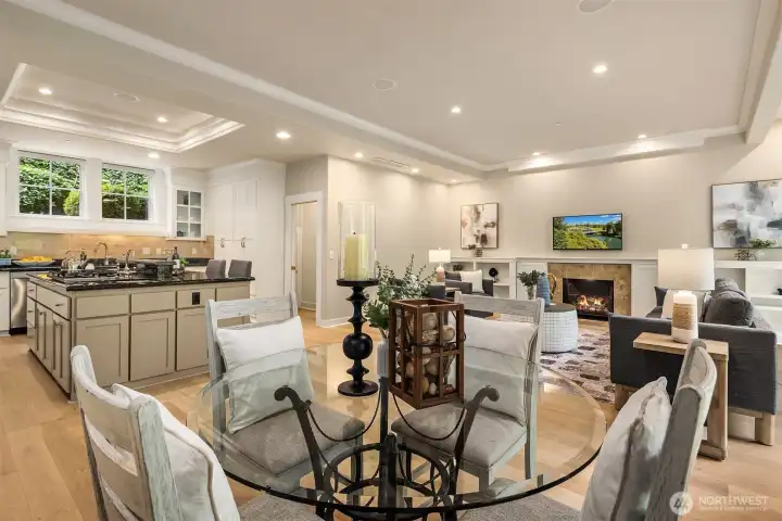 The heart of the home - where the kitchen connects to the everyday dining area and family room, with large windows framing a lush green canopy year-round.
