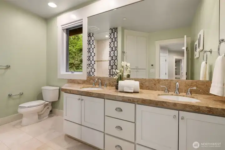 The upper bath impresses with dual sinks, marble floors and tub surround, linen closet, heated floors, and tall ceilings.