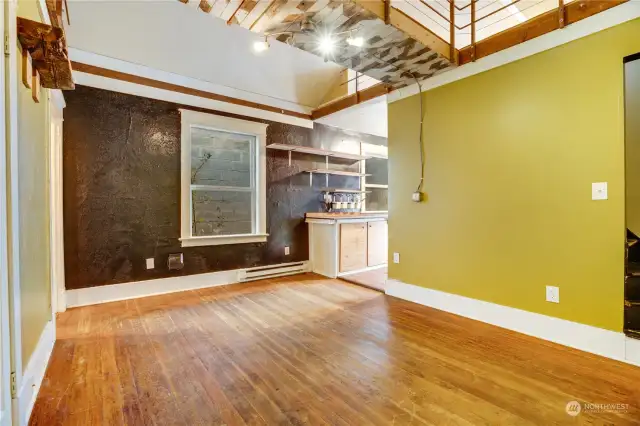 Fir floors cover the living room, front hall, and bedroom. Stairs on the right lead up to the loft.