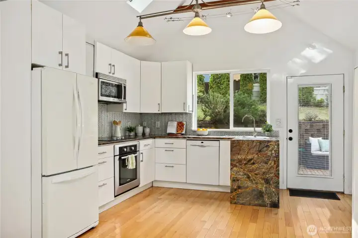 This remodeled kitchen features stone counters with a waterfall edge & beautifully tiled backsplash.