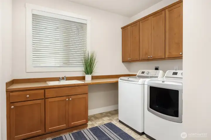 Laundry room with utility sink and abundant storage on the main level.
