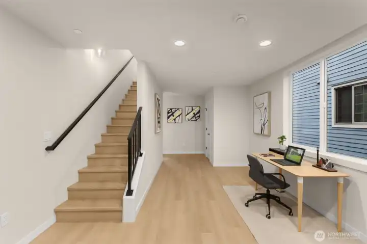 Bright and airy entry level featuring a dedicated home workspace or den, seamless garage access, and a floating staircase layout. Bright and airy entry level featuring a dedicated home workspace or den, seamless garage access, and a floating staircase layout.