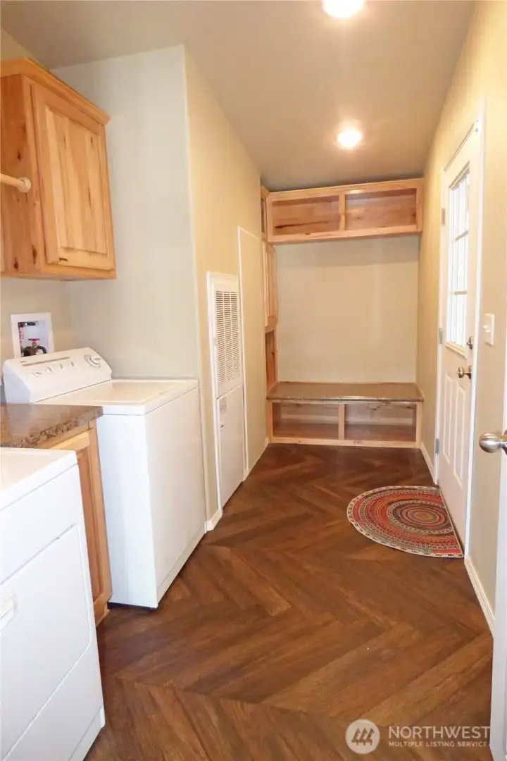Great laundry room with w/d, hot water tank, hanging bar, bench and storage. Door leads to double garage.