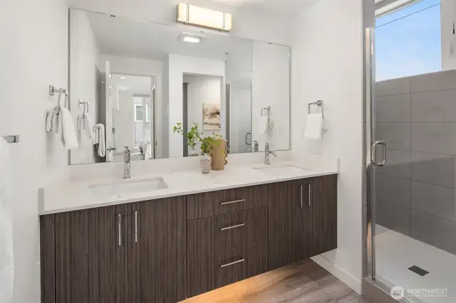 Double vanity and walk in shower flooded with natural light.