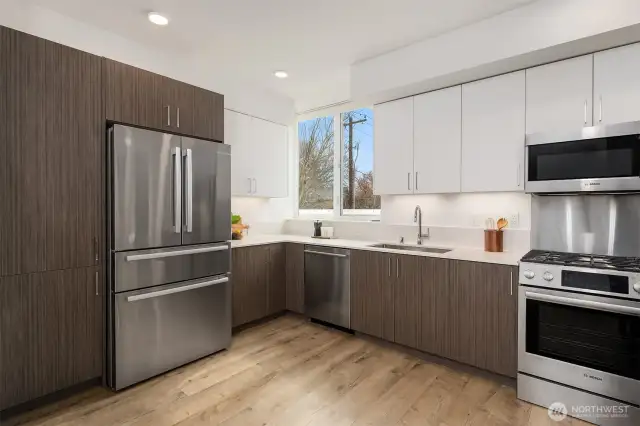 Chefs kitchen with stainless appliances and gas range.