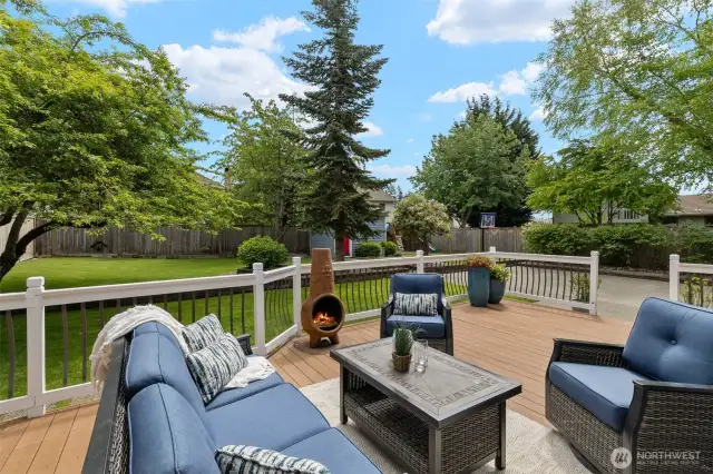 Fully fenced backyard ready for every activity: All-weather deck, level lawn and garden space, shed, playset to stay, and concrete flat top with basketball hoop!