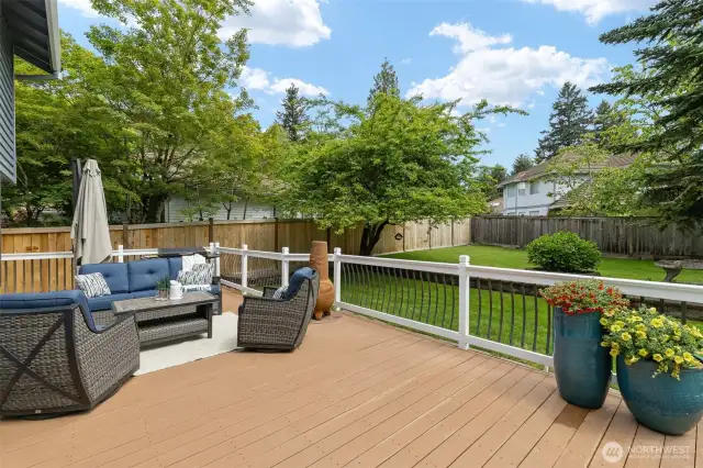 Fully fenced backyard ready for every activity: All-weather deck, level lawn and garden space, shed, playset to stay, and concrete flat top with basketball hoop!
