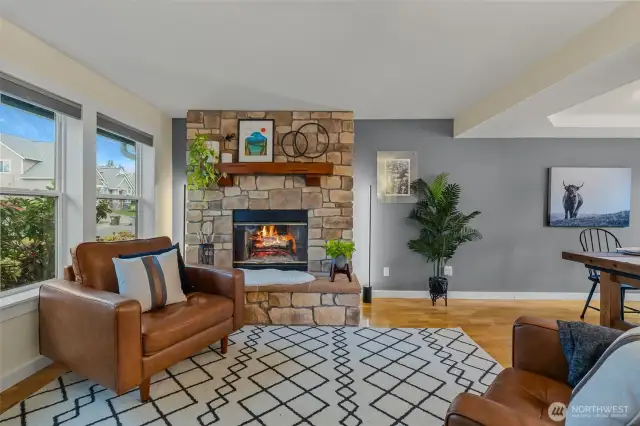 Front facing living room with tinted windows for privacy and energy efficiency, wood burning firelpace, open to dining room with continuous flow/access into kitchen.