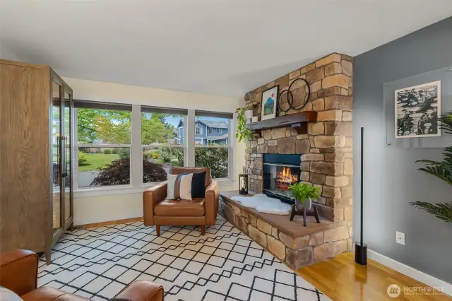 Front facing living room with tinted windows for privacy and energy efficiency, wood burning firelpace, open to dining room with continuous flow/access into kitchen.