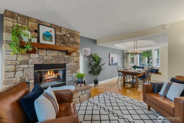 Front facing living room with tinted windows for privacy and energy efficiency, wood burning firelpace, open to dining room with continuous flow/access into kitchen.