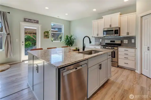 Cook, gather, and entertain with ease in this light-filled kitchen featuring a huge island, stainless steel appliances, and direct access to the backyard oasis.