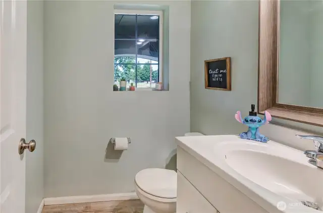 Charming and light-filled half bath with a modern vanity, natural light, and playful personality—perfect for guests!