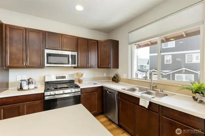 Light-filled kitchen with warm cabinetry and stainless steel appliances.