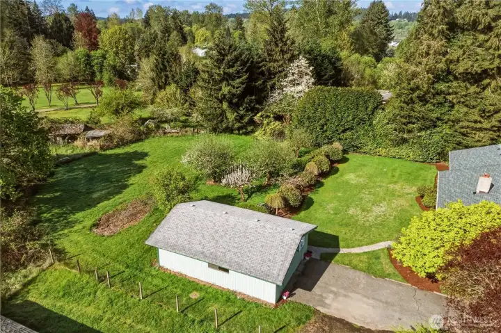 This aerial view shows the detached garage, backyard, and back pasture area.