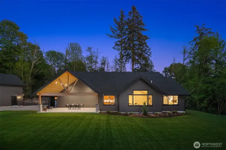 Private backyard featuring a large, level lawn, professionally landscaped grounds, and Rain Bird irrigation system. Surrounded by mature trees for exceptional privacy and a peaceful natural setting.