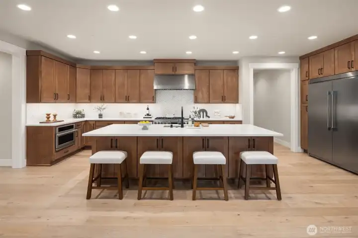 The chef’s kitchen is beautifully appointed with premium appliances and elevated finishes, including a 48” Monogram Professional double oven with six burners and griddle, Monogram microwave, Zephyr hood vent, Monogram dishwasher, and a Frigidaire Professional built-in refrigerator and freezer with ice maker.