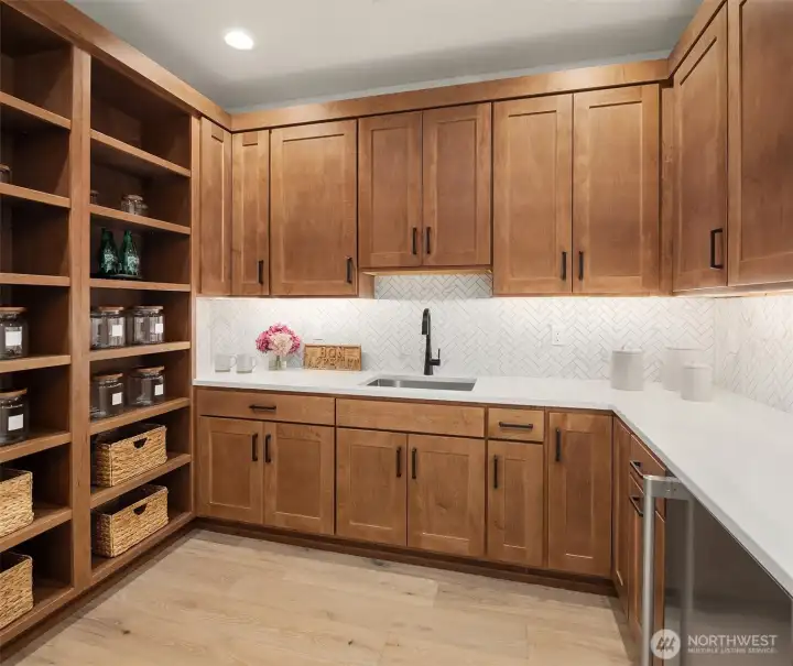 A separate beverage station in the walk-in pantry features a Monogram beverage refrigerator with ice maker, ideal for organization, storage, and beverage station.