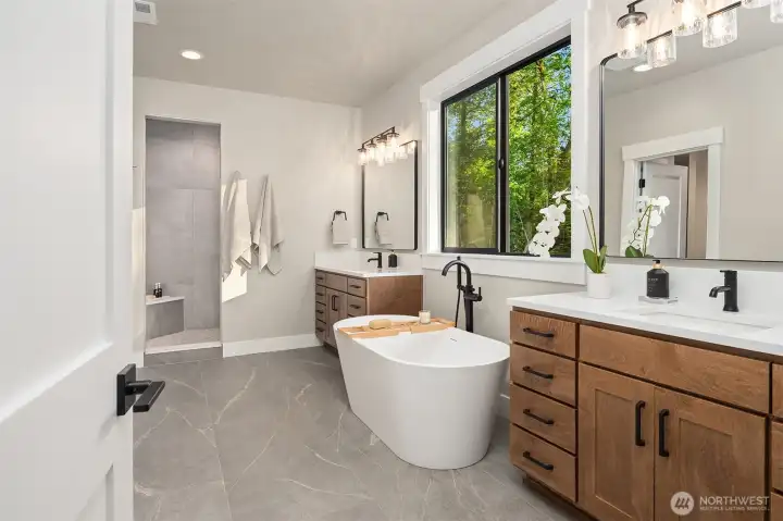 Primary bath featuring dual standalone vanities, a large soaking tub, and a walk-in shower.