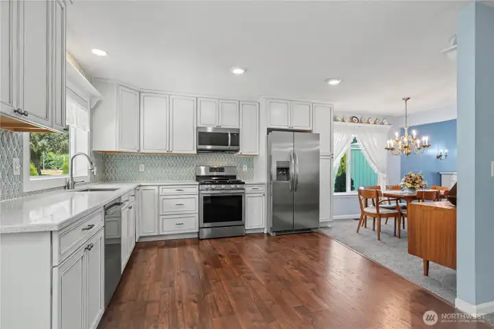Kitchen view one leading to your dining room, love the open feel - easy for dining and entertaining. Newer stainless steel appliances, love the quartz counter tops, gorgeous cabinetry and full-height tile backsplash.