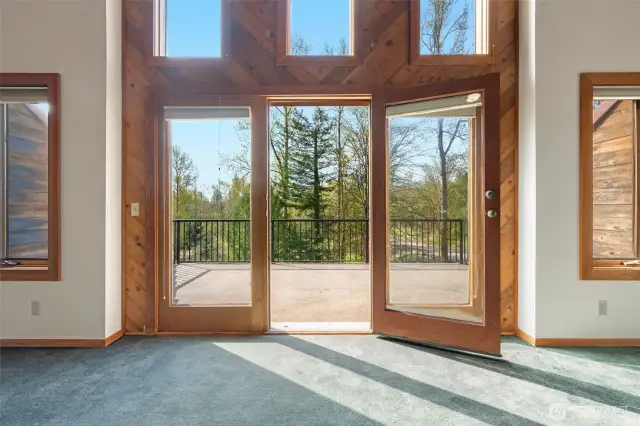French doors lead to a peaceful treetop deck, filling the room with light and possibility. Swap the carpet for new flooring and this space transforms—simple update, big impact.