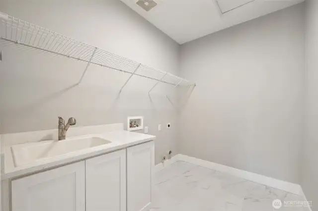 Dedicated laundry space, complete with a utility sink, cabinets, and dryer hook-up with both gas and electric.