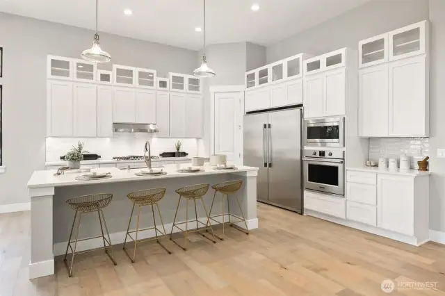 The vibrant and sophisticated kitchen dazzles with its glossy white backsplash, expanded cabinetry with glass accents, sleek stainless appliances, and slab quartz benchtops.