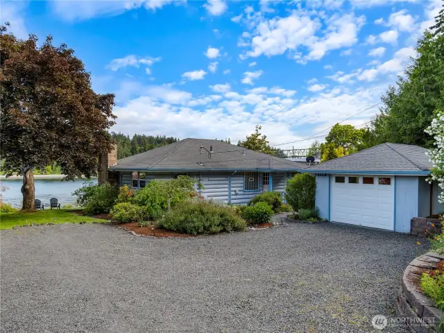 Front of the home with detached 1 car garage and gravel parking areas.