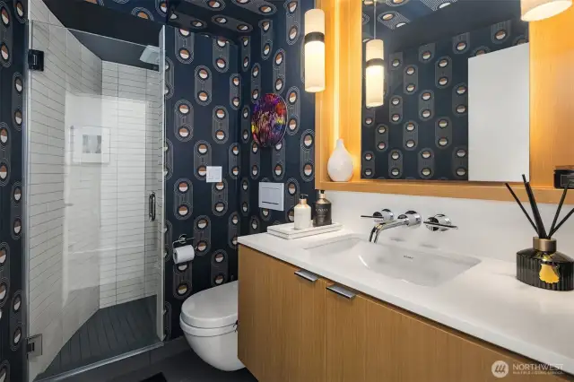 In the main floor 3/4 bath, fun wallpaper plays with classic materials and finishes.