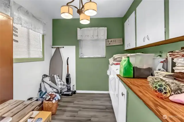 The laundry room has ample cabinets and storage space. The cabinets are a light color, and the room has a window that lets in natural light, makes the room even larger.