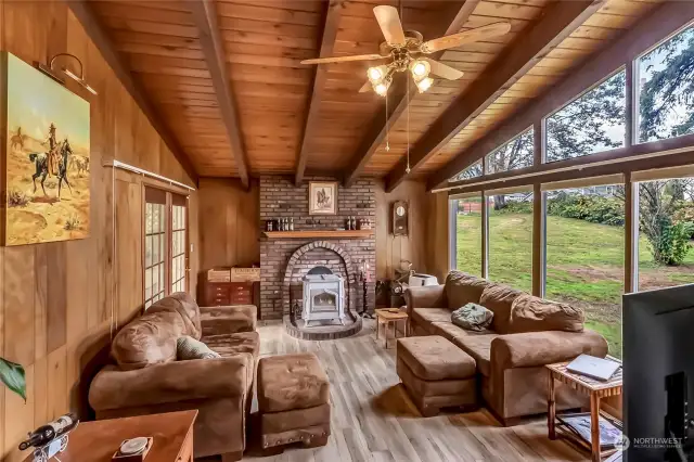 The sunken living room has high ceilings and very large windows creating a very comfortable feeling, along with wood stove and stone fireplace that makes the room toasty on these chilly nights. French doors lead out to the covered patio.