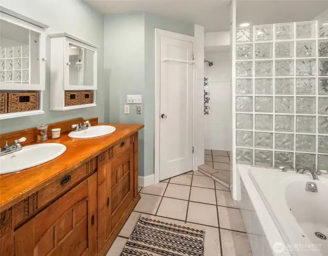 The primary bathing area with soaking tub and tiled walk-in shower. W/C has it's own private room with pedestal sink.