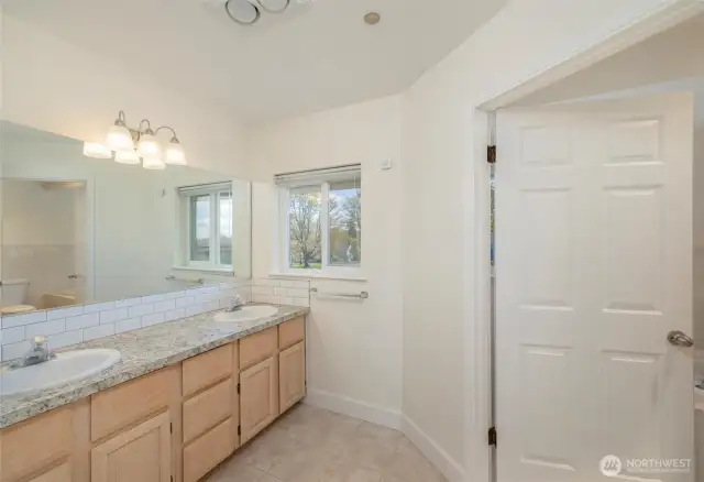 Double vanity ensuite, with soaking tub, shower, and toilet through doorway.