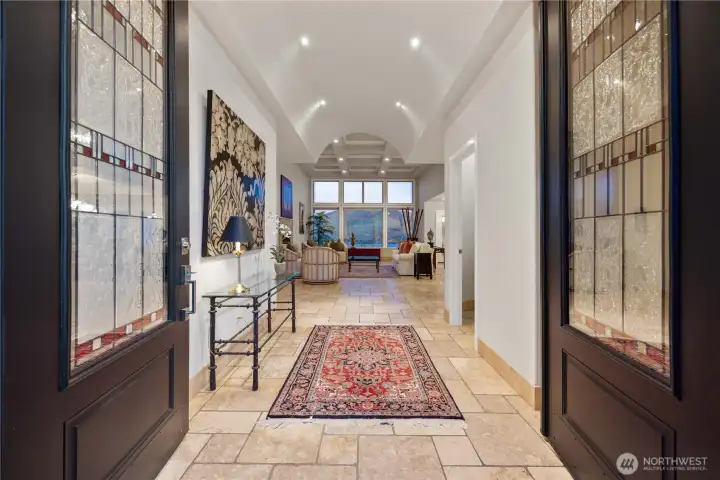 Grand, light-filled entry sets the tone with soaring ceilings, rich accents, and elegant double doors. A long, inviting hallway draws you in with warm natural light, art niches, and a statement runner, creating a refined first impression and seamless transition into the home’s main living spaces.