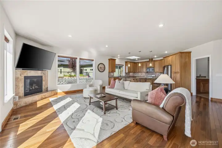 Open-concept great room seamlessly connecting the living area and kitchen, designed for effortless everyday living and entertaining. Warm hardwood floors, abundant natural light, and expansive windows frame stunning Lake Chelan and mountain views, while the cozy fireplace anchors the space. The kitchen features rich cabinetry, ample counter space, and a functional layout that keeps you connected to the heart of the home.