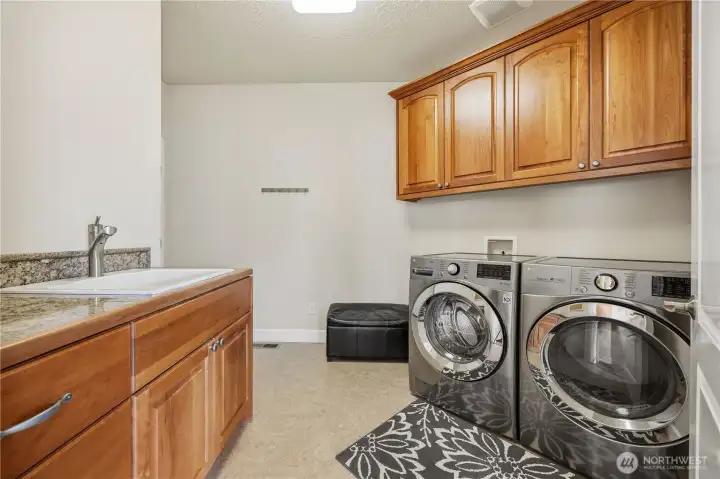 Functional laundry room with ample cabinetry for storage and counter space for folding and organization. This efficient space is designed to make everyday tasks convenient and streamlined.