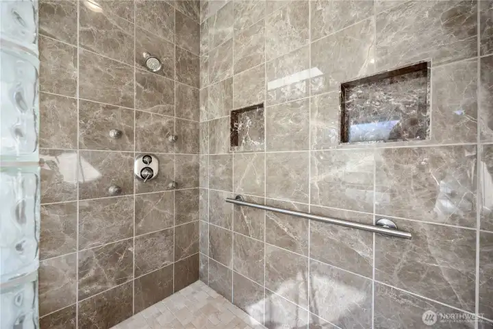 Spa-inspired primary ensuite featuring a massive walk-in shower with dual shower heads, elegant tile surrounds, and built-in niches. Designed for a luxurious experience, this expansive shower retreat blends modern finishes with functionality for everyday comfort.
