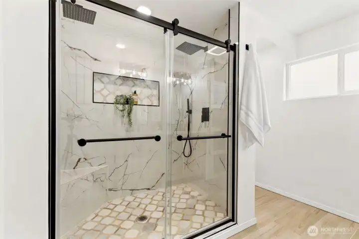Indulge in the stunning oversized walk-in shower featuring elegant tilework and sleek black hardware accents.
