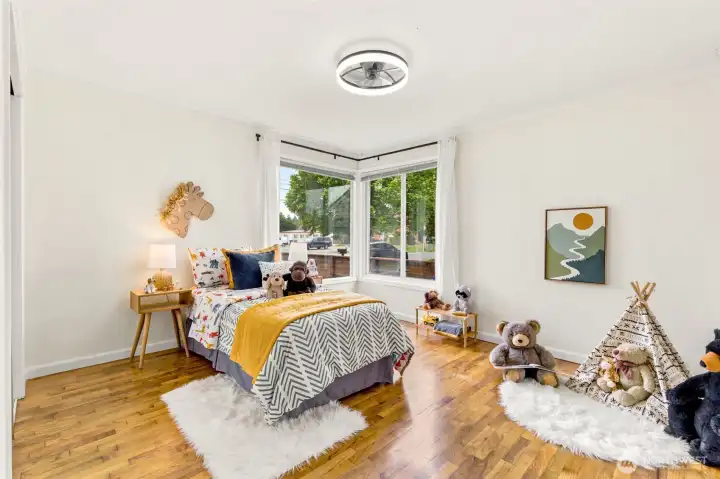 Bright corner windows fill this inviting bedroom with natural light, creating a cheerful and comfortable space.