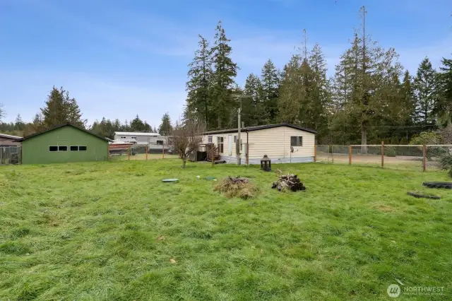 View from back corner of level yard. Green 2-car detached garage on left