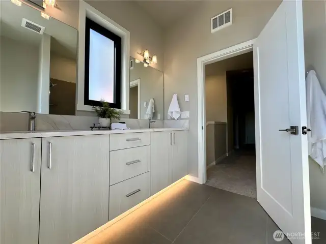 Upstairs guest bath filled with natural light, quartz counters, double vanity and tiled tub/shower combo