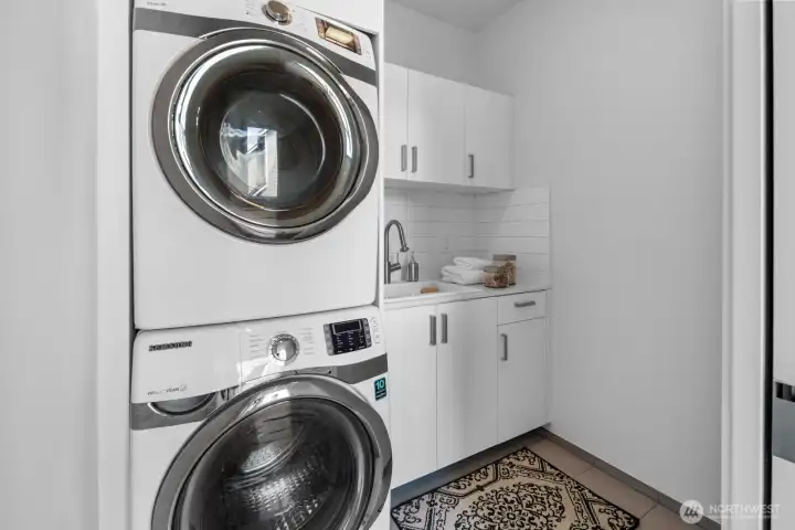 Laundry room with stacked Samsung washer & dryer, built-in cabinetry and a deep laundry sink