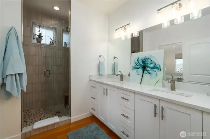 Primary bathroom has dual sinks and a custom tiled shower.