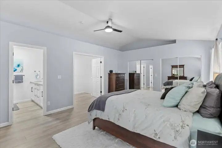 Primary bedroom featuring elegant French door entry, vaulted ceilings, a private ensuite bathroom, and an abundance of natural light. Primary bedroom featuring elegant French door entry, vaulted ceilings, a private ensuite bathroom, and an abundance of natural light.