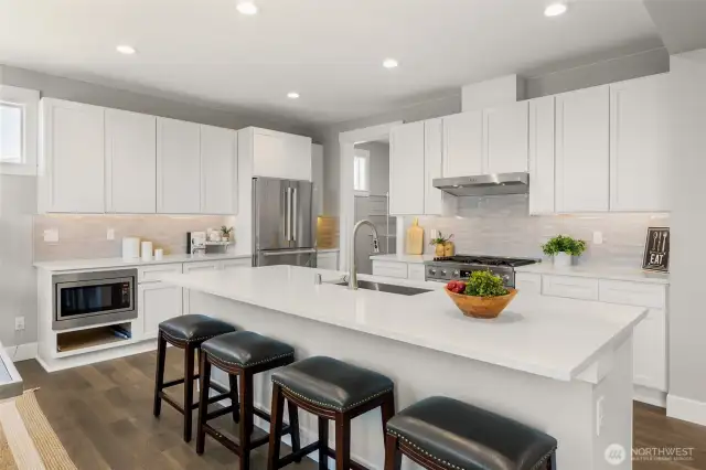 The sparkling dream kitchen is equipped with sleek stainless appliances, full tile backsplash, slab quartz, and huge walk-in pantry.