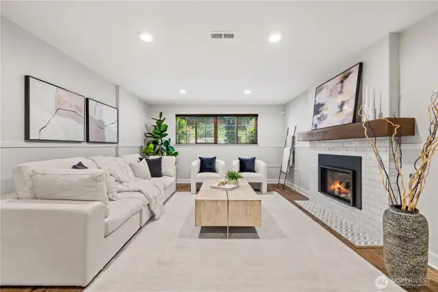 The lower level features a generous second living area with a cozy fireplace, ideal for a playroom, home office, or a welcoming space for guests to unwind