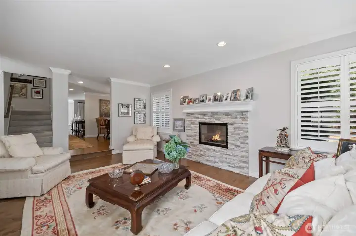 From this perspective, the sunken living room opens gracefully toward the kitchen and dining areas, showcasing the home’s open-concept layout. The hardwood floors flow seamlessly throughout, while large windows fill the space with natural light, highlighting the elegant finishes and inviting ambiance. This view emphasizes the perfect balance between intimate living spaces and social, entertaining areas, making it ideal for family gatherings or hosting guests.