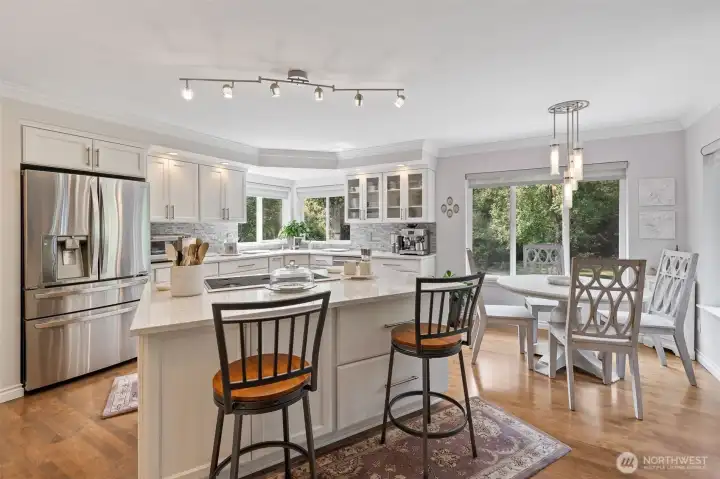 The remodeled kitchen is a showpiece of both style and function. Rich hardwood floors flow throughout, complementing the crisp design and open layout. Top of the line stainless steel appliances gleam beneath timeless cabinetry and sleek countertops, offering the perfect blend of elegance and modern convenience. A spacious island anchors the room, ideal for meal prep, casual dining, or gathering with friends and family. Designed with both the home chef and entertainer in mind, this kitchen is truly the heart of the home.